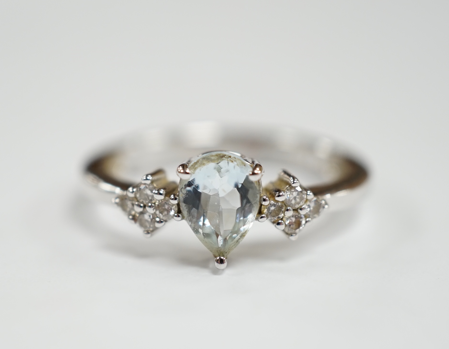 A modern Italian Comete 18k white metal and single stone pear cut aquamarine set ring, with eight stone diamond cluster set shoulders, size N, gross weight 3.3 grams.
